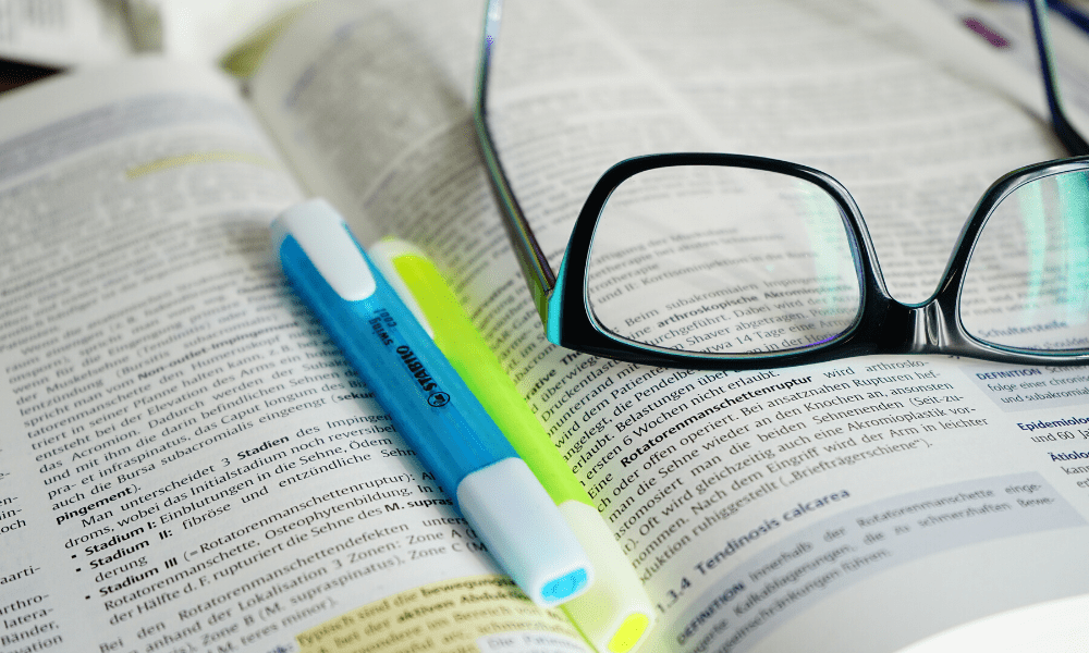 open book with highlighters and glasses on top