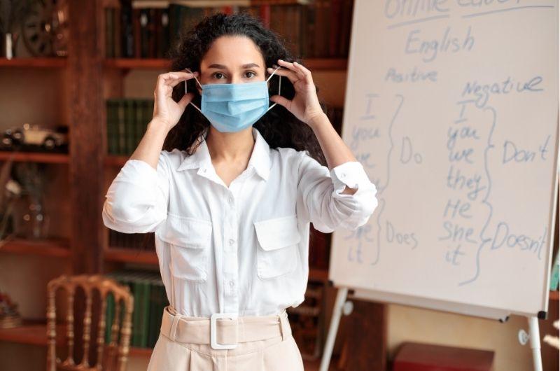 teacher wearing a mask in front of white board